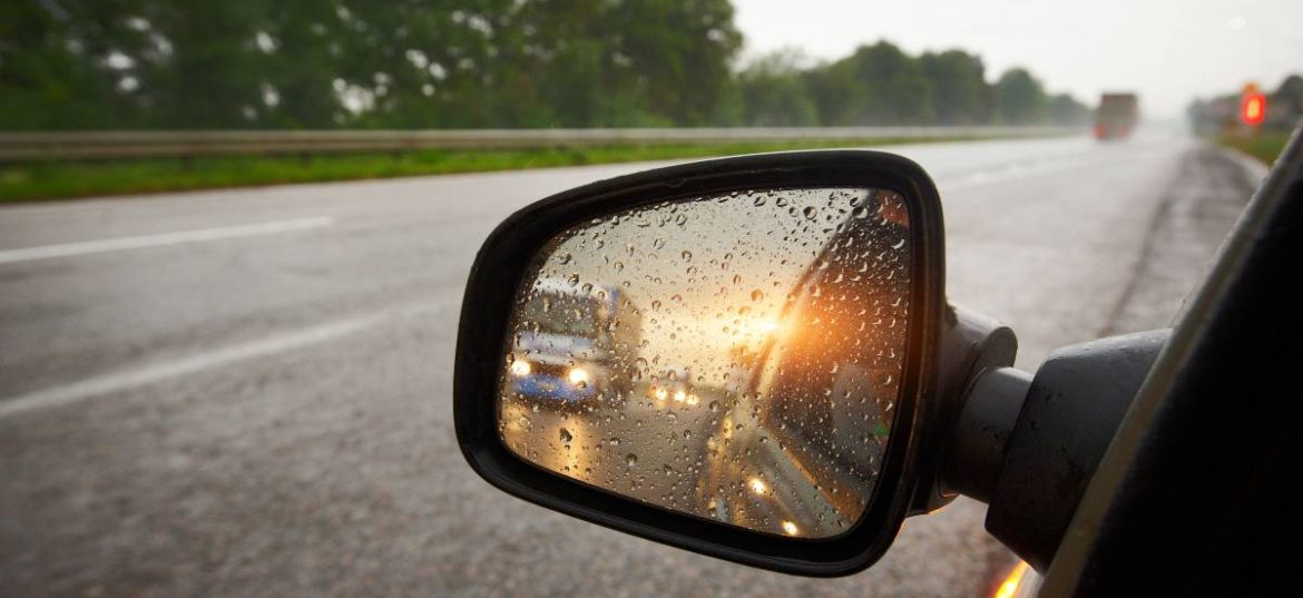 rétroviseur avec un coucher de soleil des feux de voiture et de la pluie.